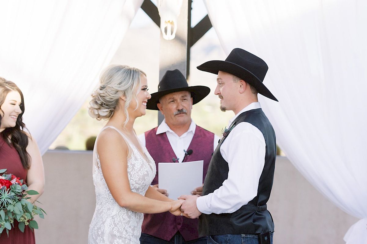 The image shows a wedding ceremony with a bride, groom, and officiant dressed in Western attire, with a bridesmaid smiling on the left.