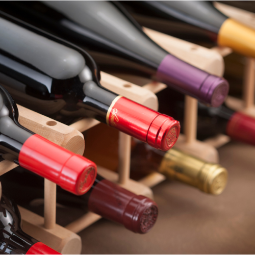 The image shows bottles of wine on a wooden rack, stored horizontally.