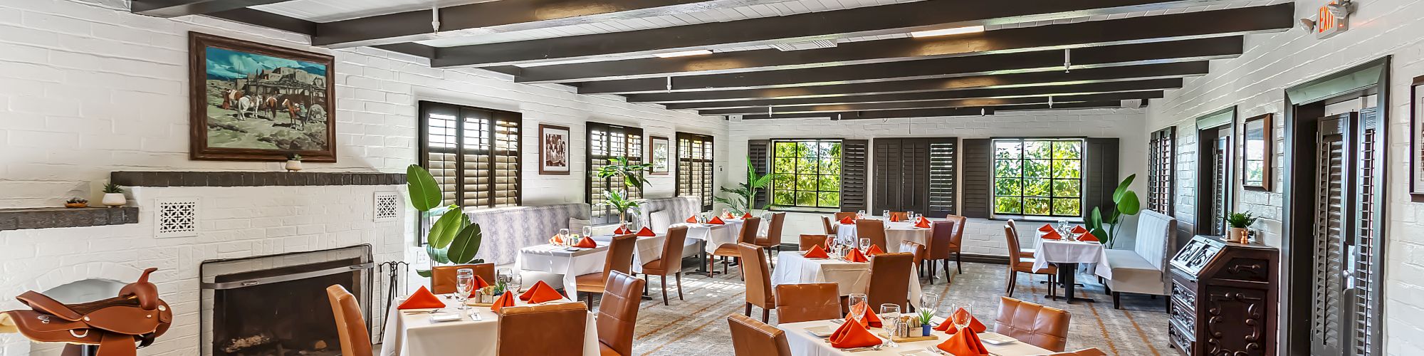 This image shows a spacious, bright restaurant with neatly arranged tables and chairs, featuring a rustic interior with exposed beams and large windows.