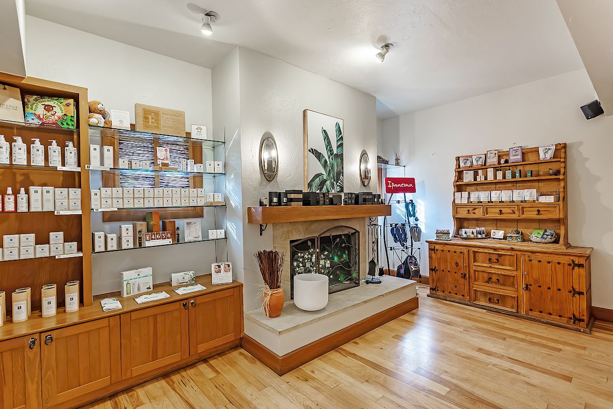 This image shows a cozy store interior with wooden shelves displaying various products, a central fireplace, and wooden flooring, creating a warm atmosphere.